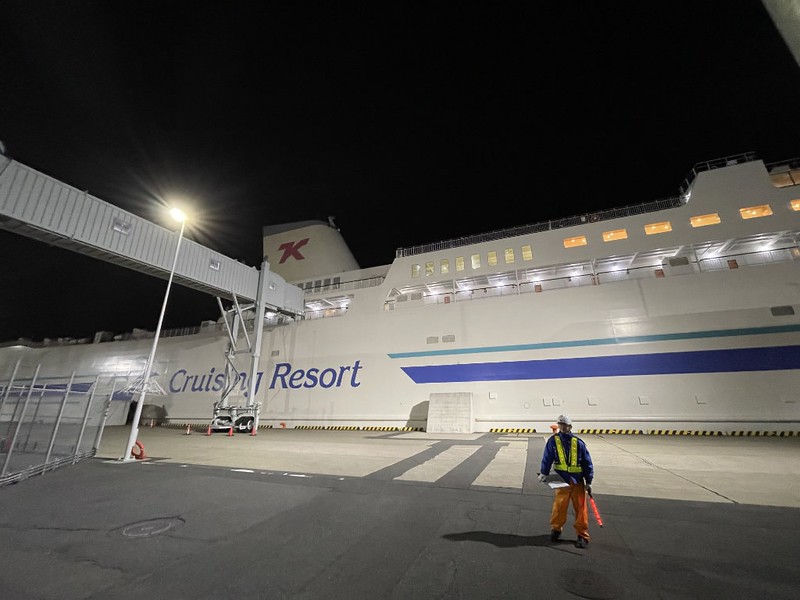 Side view of the Ferry Soleil docked at the Tokyo Kyushu ferry terminal with a docker worker on the quay and the passenger gangway overhead