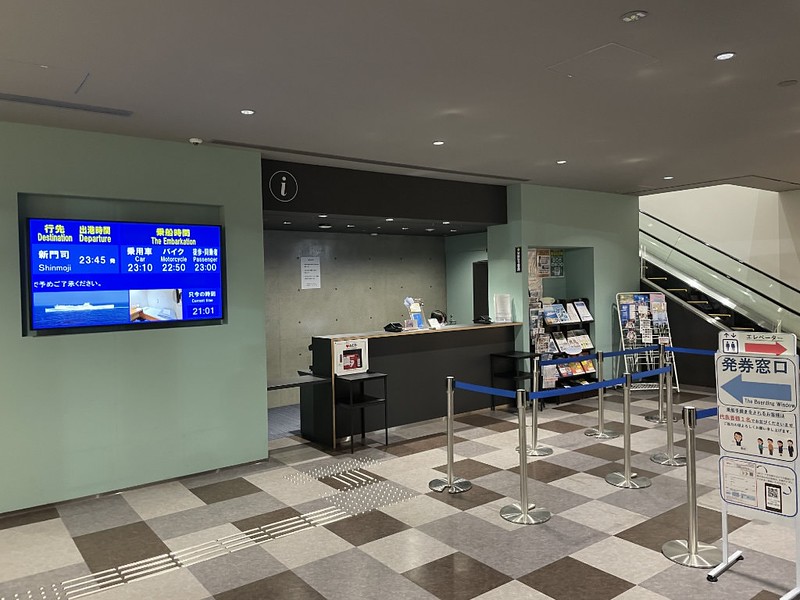 Ticket counter inside the Tokyo Kyushu ferry terminal with information stands and departure board