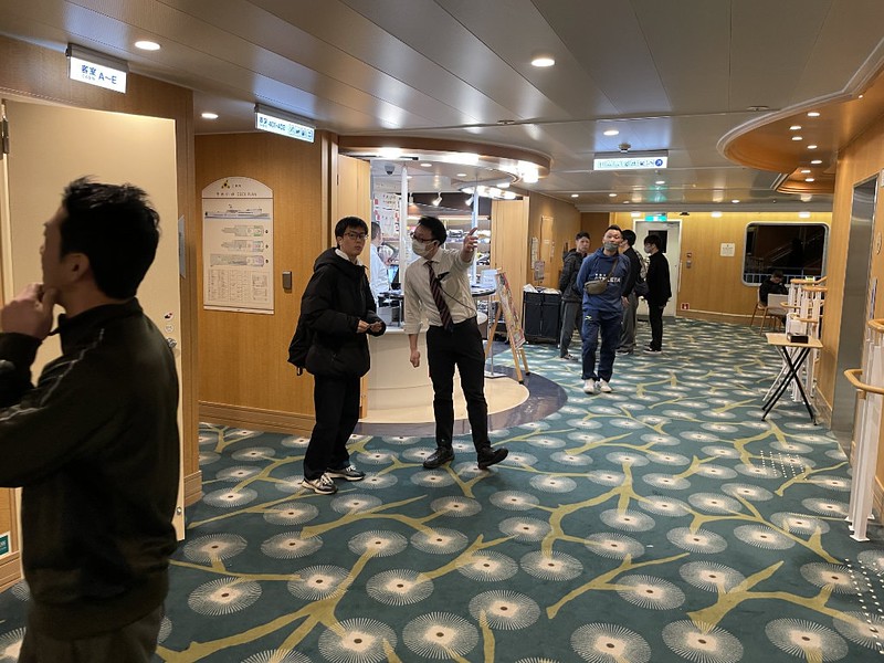 A member of staff in a hygiene face mask directs the public in the lobby area of the Ferry Soleil
