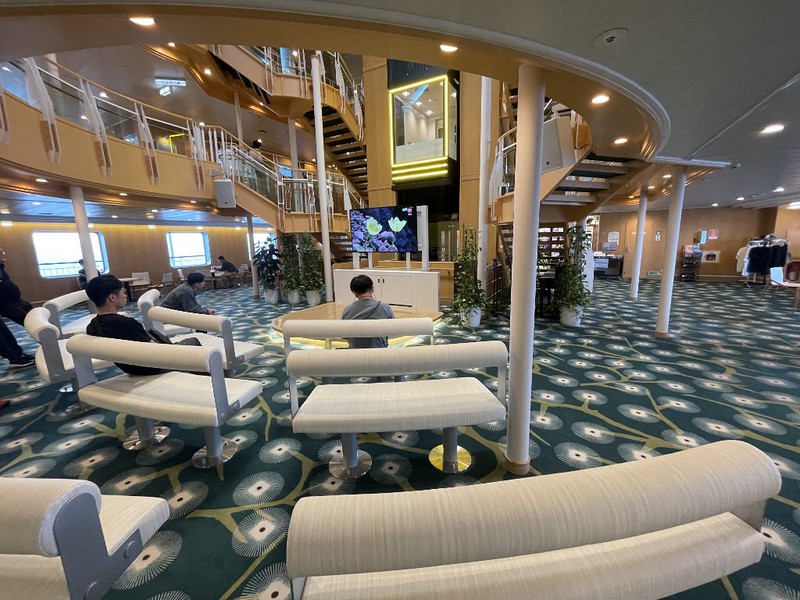 A few people sat on bench sofas watching a television in the main atrium of the Ferry Soleil