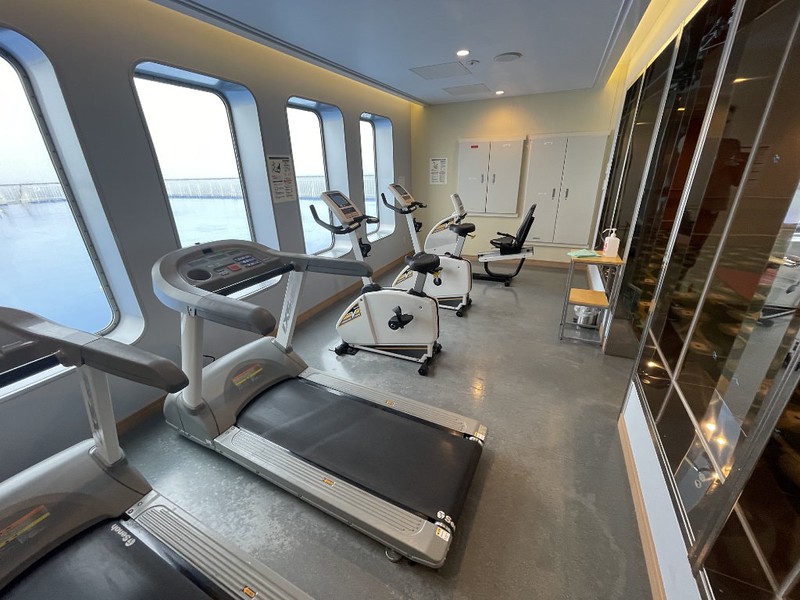 Small exercise room on the Ferry Soleil with treadmills and exercise bikes and windows looking out over the front of the ship