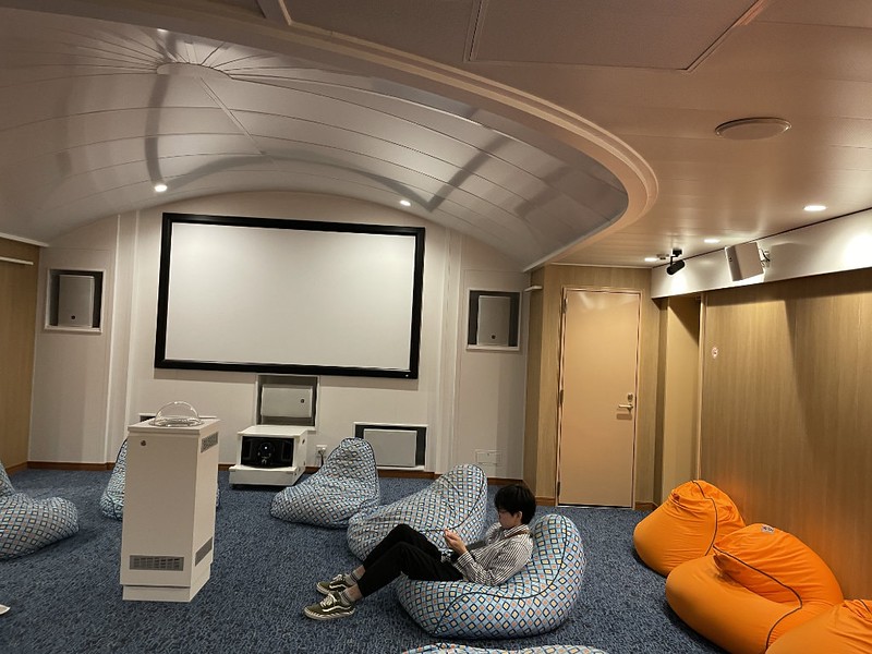 A passenger checks their phone on one of the bean bags on the floor of the Ferry Soleil screening room