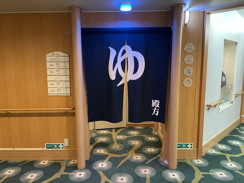 Blue entrance curtain and information about the men’s bath on the Ferry Soleil, Japan
