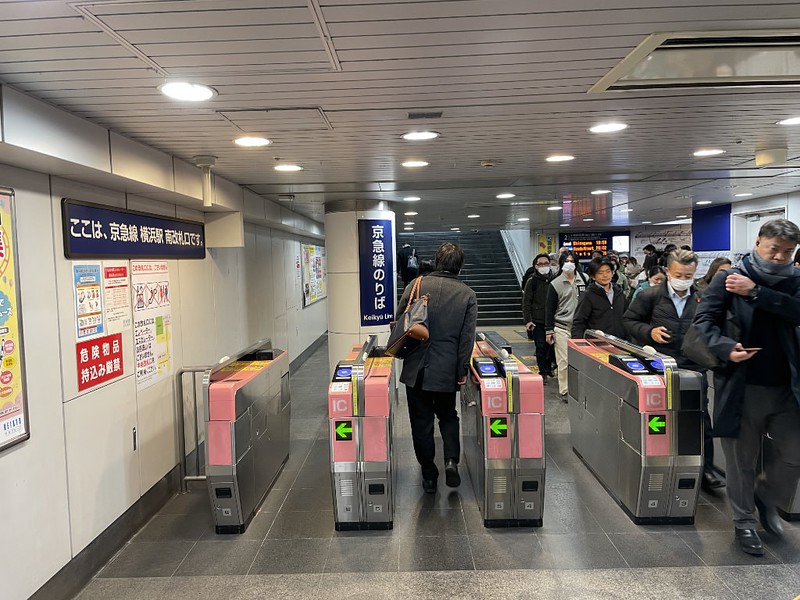 People passing through the pink IC card ticket barriers for the Keikyo Line at Yokohama Station