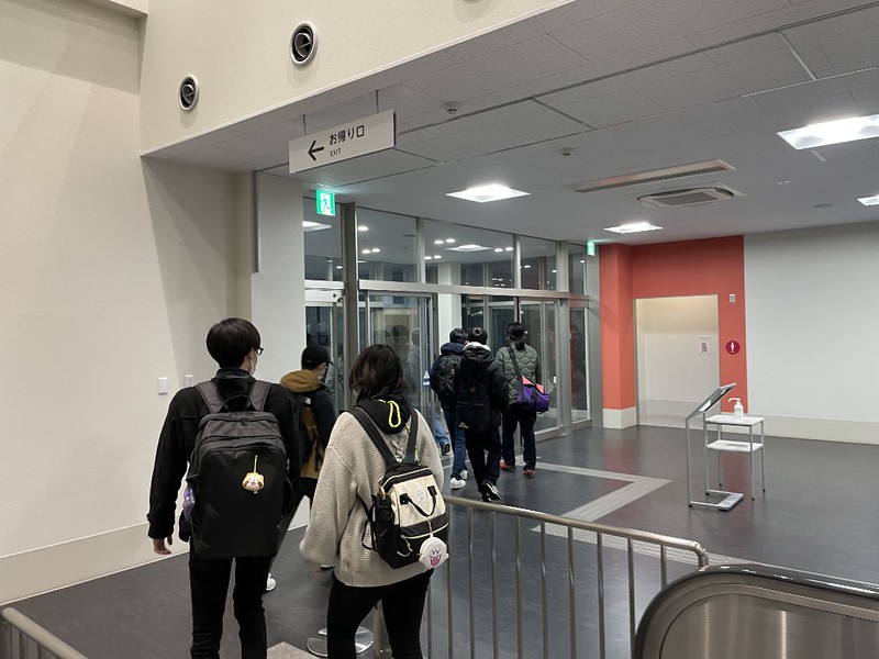 A line of passengers walk through the Shinmoji ferry terminal building towards the exit