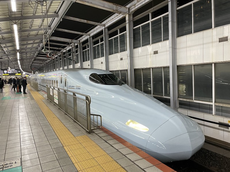 Long view from the nose of the Shinkansen headed to Hakata (Fukuoka) and people on the platform waiting to board the train