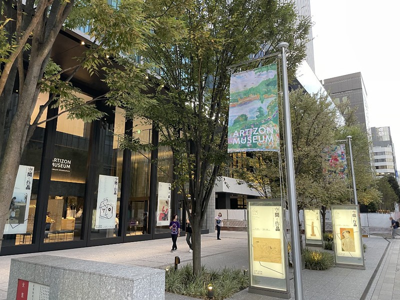 Angled view of the signage in the street outside the Artizon Museum in Tokyo, Japan, and exhibition posters in the glass entrance way to the building Angled view of the signage in the street outside the Artizon Museum in Tokyo, Japan, and exhibition posters in the glass entrance way to the building