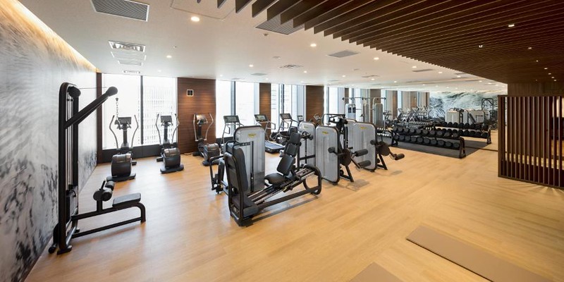 The modern gym in the Ascott Marunouchi Hotel with treadmills, spin bikes, weights, and other equipment