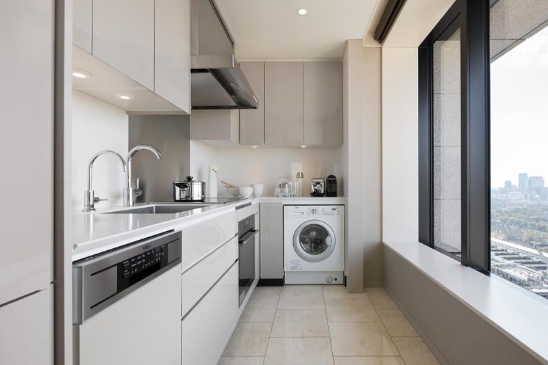 The kitchen area of a guest suite in Ascott Marunouchi Hotel with washing machine, oven and hob, and dishwasher