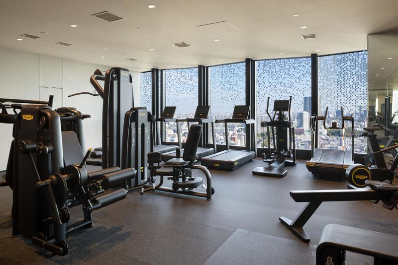 Gym equipment including treadmills and weight machines in the Bellustar Tokyo with city views outside