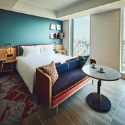 The sofas, easy chairs, and umbrellas on the rooftop outdoor lounge in the Hotel Indigo Tokyo Shibuya on a sunny day