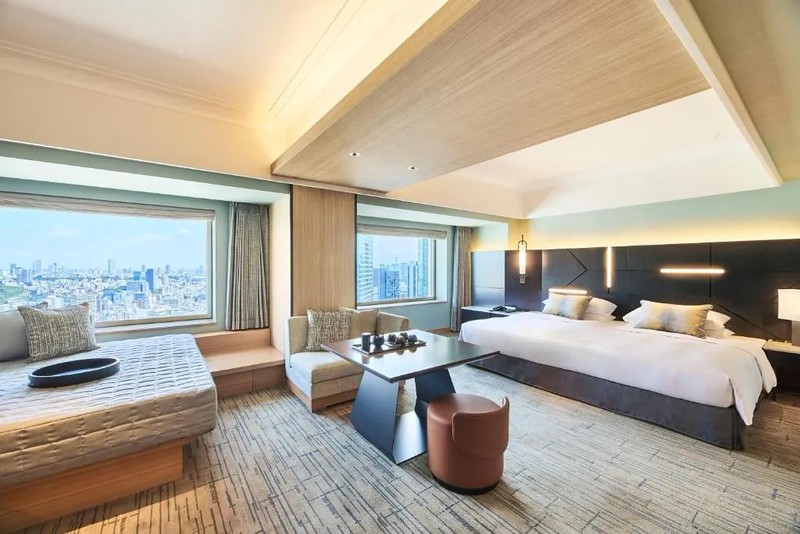 Large double suite in the Cerulean Tower Tokyu Hotel in Tokyo, Japan, with huge bed, various cushioned seating areas, and wide windoes offering city views