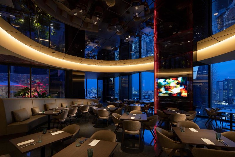 The atmospherically-lit lobby lounge of Hotel Groove Shinjuku with evening views of Tokyo