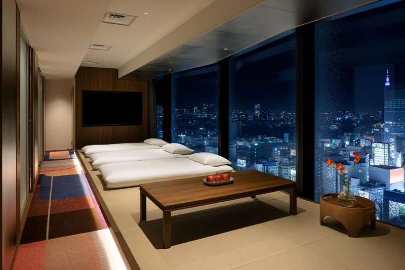 Triple room in the Hotel Groove Shinjuku with futon-style mattresses and stunning nighttime views of Tokyo