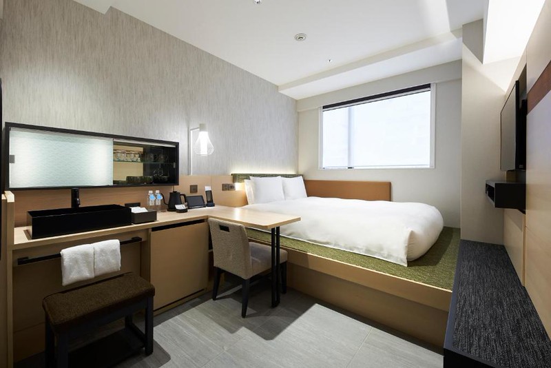 Compact guest room with mattress on raised platform and desk area in the Hotel 1899 Tokyo