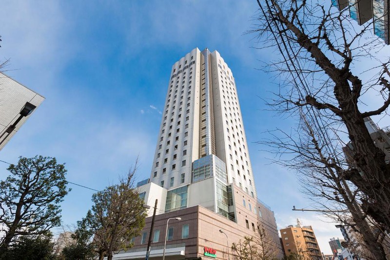 The tower of the Hundred Stay Tokyo Shinjuku hotel seen from the street on a sunny day