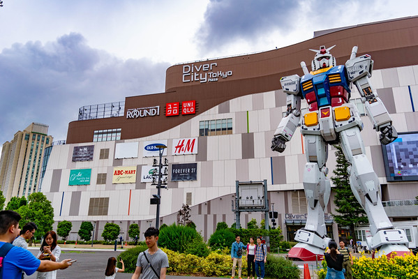 Visitors pose for photos in front of a huge Gundam Statue outside the Diver City shopping mall in Odaiba, Tokyo, Japan