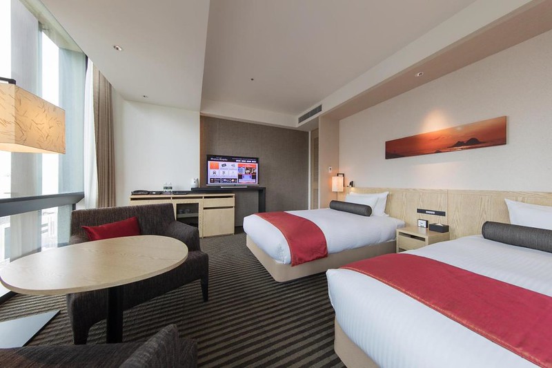 Two large beds and small living area in a twin guest room in the JR Kyushu Hotel Blossom Shinjuku, Tokyo, Japan