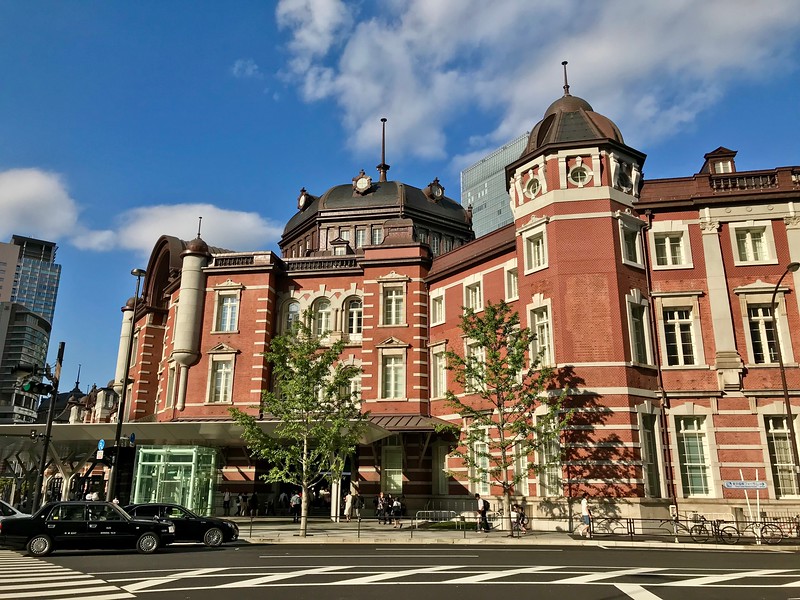The distinctive red early-20th-century façade of Tokyo Station, seen from across the road, on a sunny day