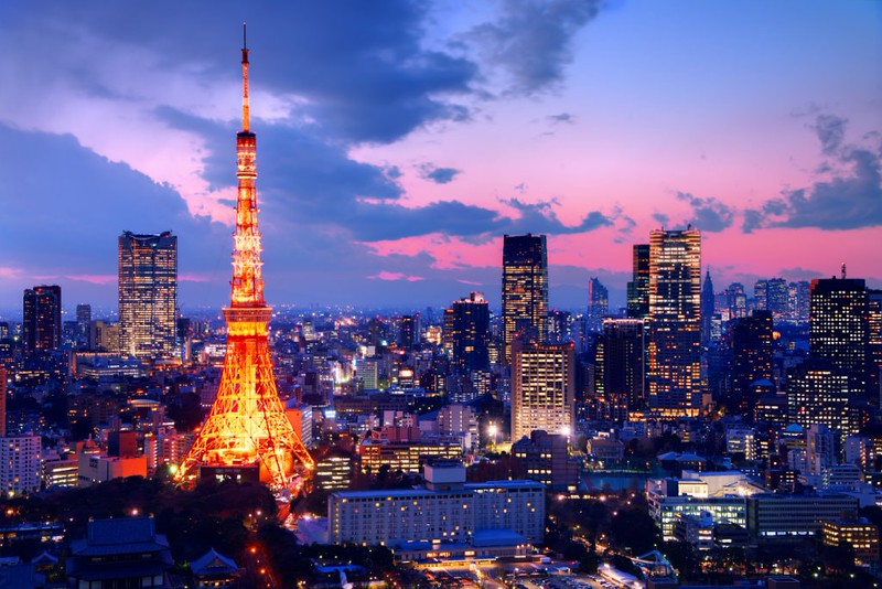 Tokyo’s urban skyline, featuring the Tokyo Tower, illuminated at twilight against a huge purple sky