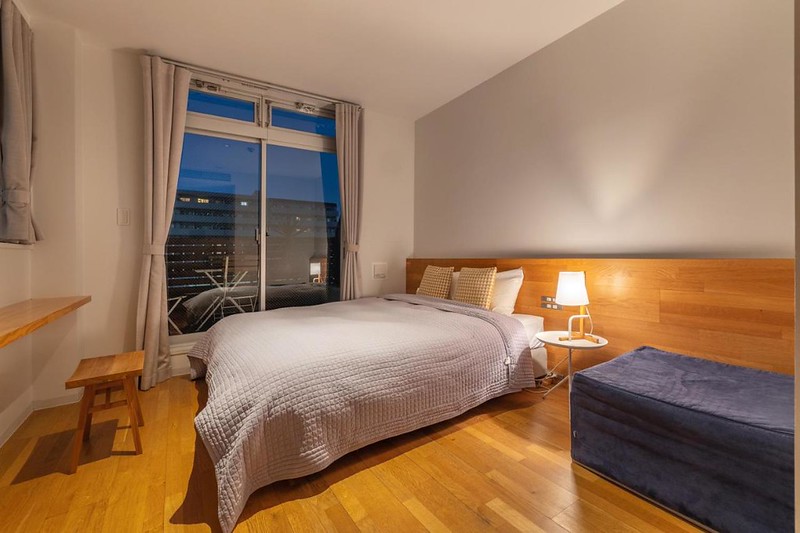 Double bed with waffle bedding and clean wooden floors in a guest room of the Unplan Kagurazaka hotel, Tokyo, Japan