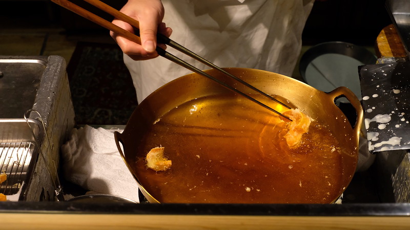 Lifting carrot slices out of hot sesame oil.