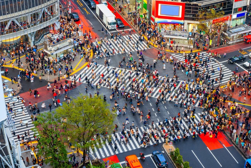 Seen from high above, a mass of people move around the famous crosswalk in Shibuya, Tokyo, Japan, as the traffic temporarily stops in the late afternoon