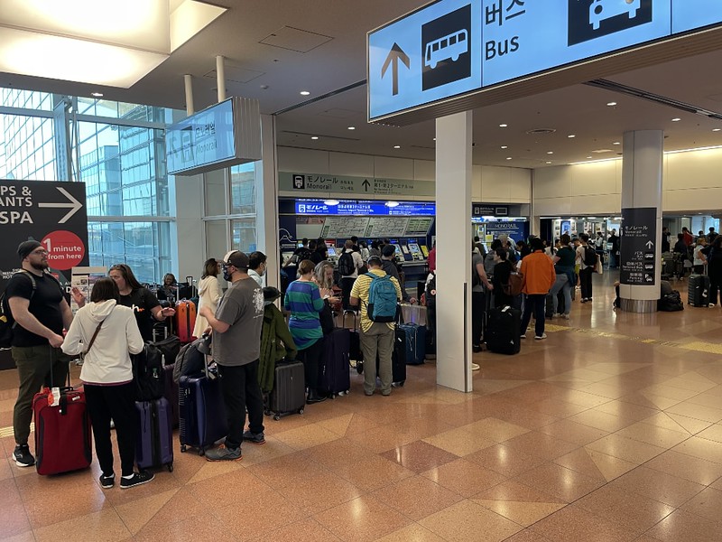 A long line of travellers with luggage wait to use a ticket machine at Tokyo’s Haneda Airport