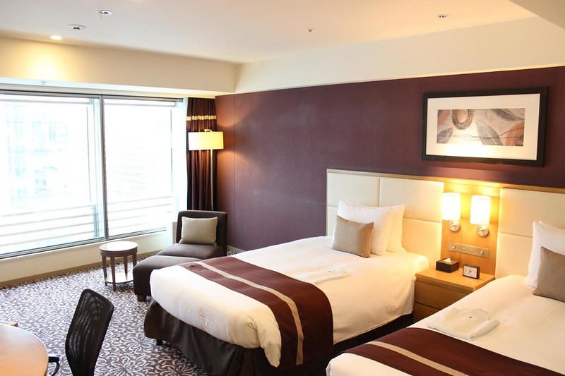 Large single beds and chaise longue in a twin guest room in the Hotel Ryumeikan Tokyo, Japan