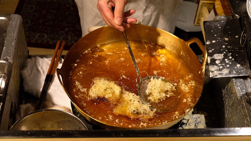Scooping bits of batter out of the hot oil.