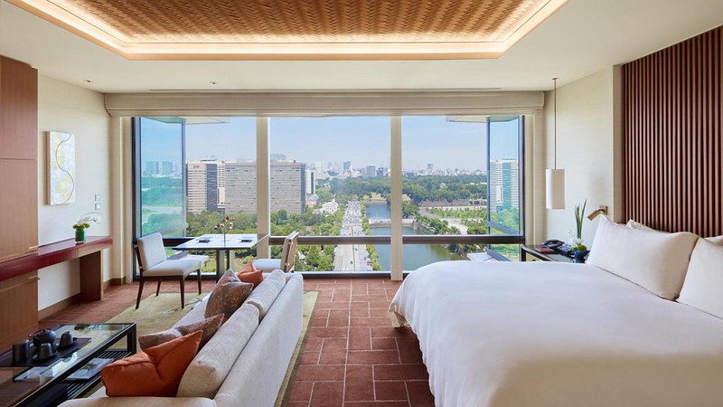 Large double bed, comfortable living area, and wall-length windows with expanisve city views in a Peninsula Tokyo hotel guest room, Japan Large double bed, comfortable living area, and wall-length windows with expanisve city views in a Peninsula Tokyo hotel guest room, Japan