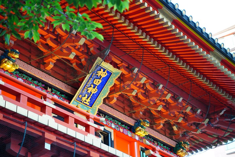 Side view of the underside of the roof of the gate of the bright-red Kanda-myojin shrine in Tokyo, Japan, with Japanese lettering