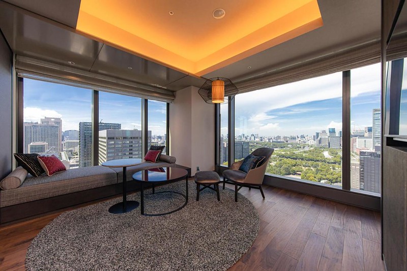 Corner window living area with views over the Tokyo skyline and parklands in a Blossom Hibiya hotel suite, Japan