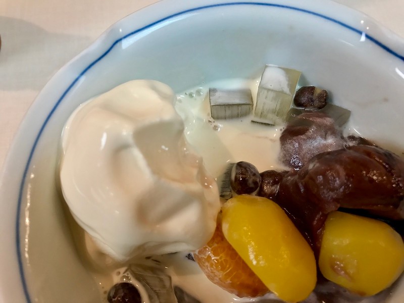 A close-up of the various textures - ice cream, translucent jelly cubes, whole beans, red bean paste, smooth chestnut, a tart slice of mikan orange.