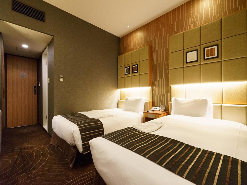 Twin guest room in the Sotetsu Fresa Inn Higashi Shinjuku hotel, Tokyo, Japan, with dark brown and green interiors and padded headboards
