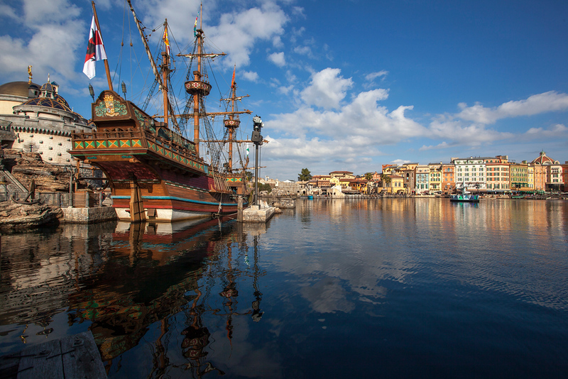 A view across the water with a replica galleon ship at Tokyo DisneySea on a blue, clear day