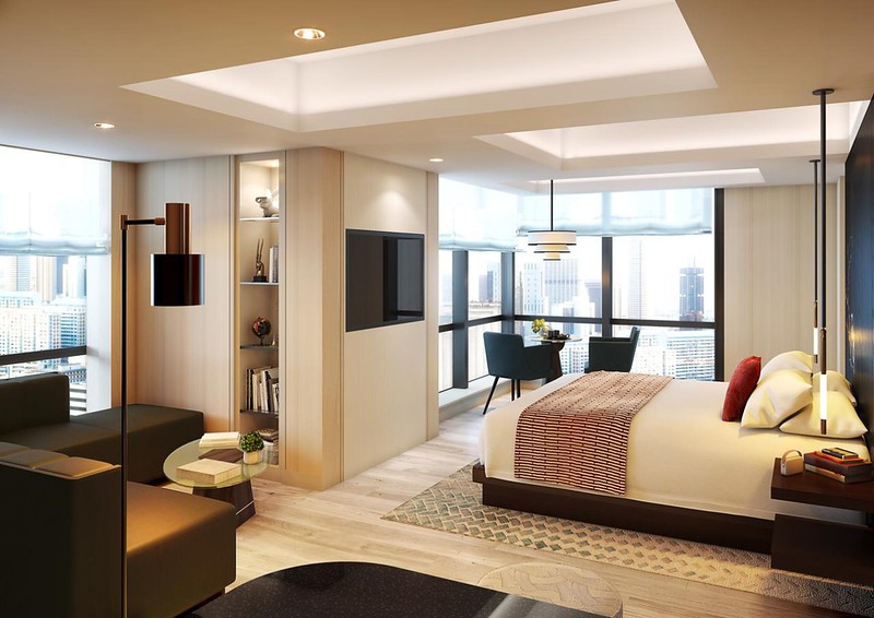 Corner guest room in the Kimpton Shinjuku hotel, Tokyo, Japan, with contemporary interior design with double bed, L-shaped leather sofa, and corner seating area