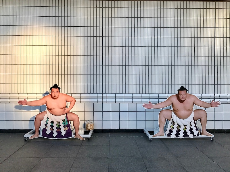 Cardboard cutouts of sumo wrestlers at the entrance to the stadium.