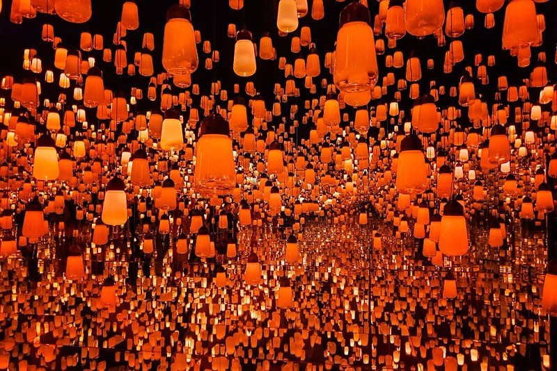 Dozens of hanging, reflected orange lights reflected in mirrors to create an infinite view at Tokyo’s Teamlab Borderless Museum
