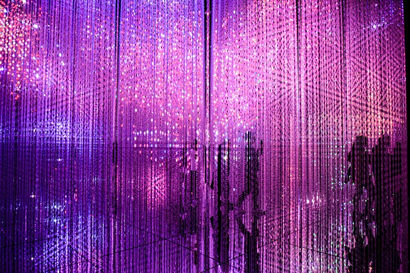 Visitors pass through a shimmering grid of purple and mauve lights at the teamLab Planets art experience in Tokyo, Japan