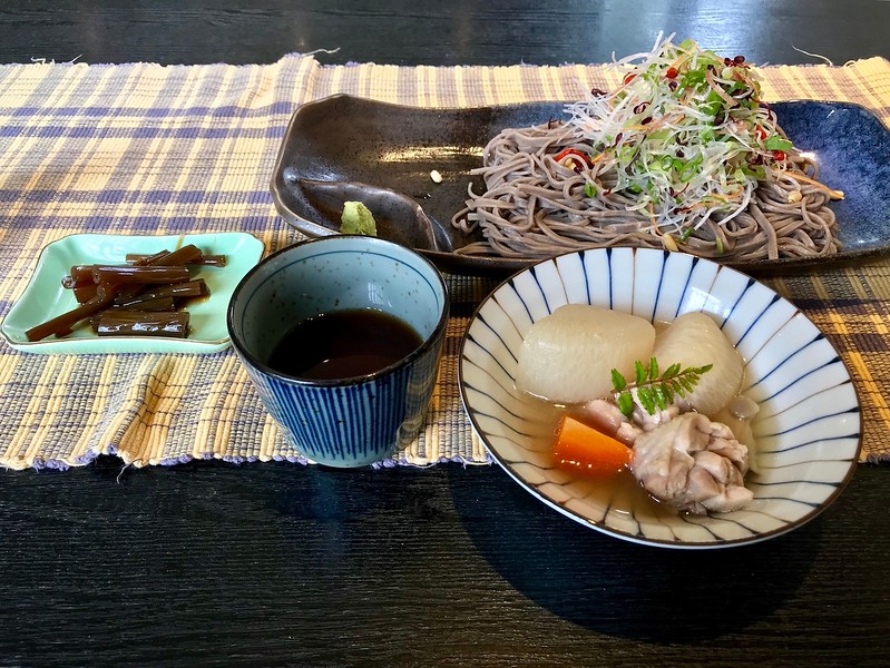 Soba buckwheat noodles with vegetables, simmered chicken and root vegetables, braised butterbur stalks, and a noodle dipping sauce.