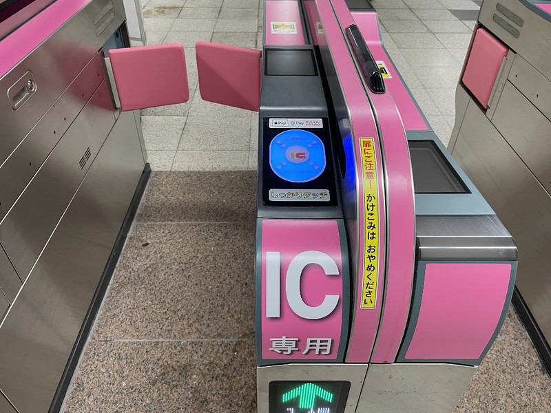Pink ticket barrier at a Tokyo train station with a touchpad for tapping in with an IC card
