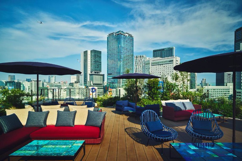 The sofas, easy chairs, and umbrellas on the rooftop outdoor lounge in the Hotel Indigo Tokyo Shibuya on a sunny day The sofas, easy chairs, and umbrellas on the rooftop outdoor lounge in the Hotel Indigo Tokyo Shibuya on a sunny day