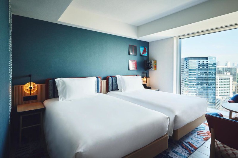 Large twin beds and a view of nearby buildings in a premium king room in the Hotel Indigo Tokyo Shibuya