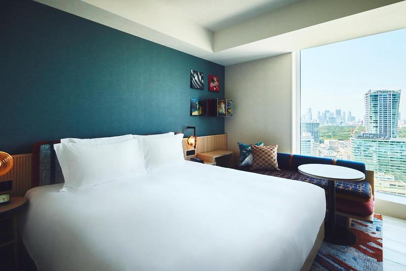 Large double bed and a view of nearby buildings in a premium room in the Hotel Indigo Tokyo Shibuya