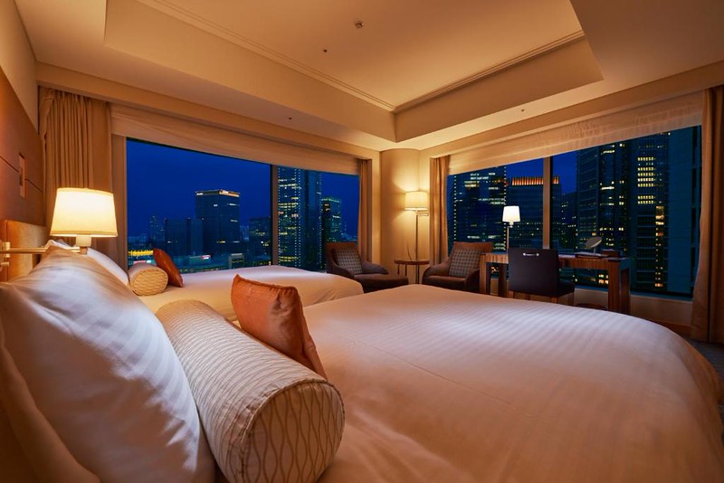 Big comfortable twin beds in a corner room of Tokyo’s Marunouchi Hotel with a nighttime view of the city
