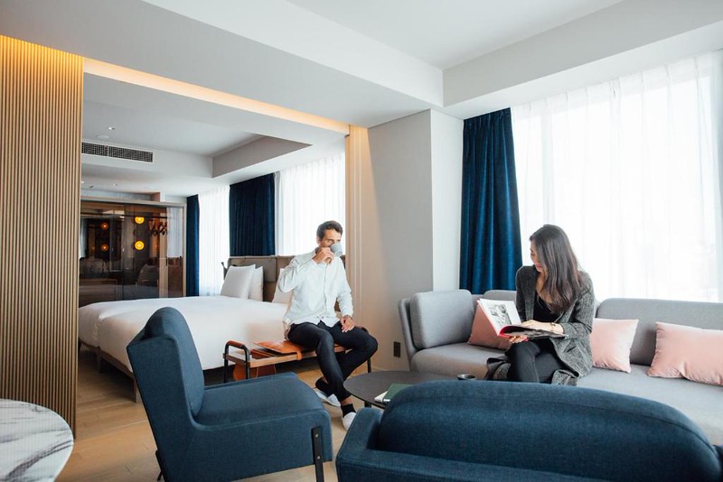 A couple enjoys a coffee and a guide book in the living area of a double suite room in the Nohga Hotel Tokyo Ueno