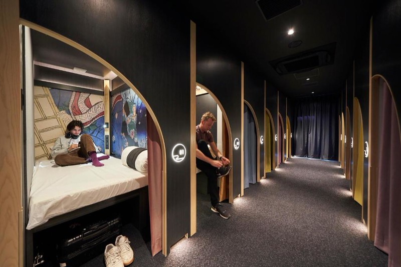 People sat on the beds in full-height sleeping capsules in the Resol Poshtel Tokyo Asakusa, Tokyo