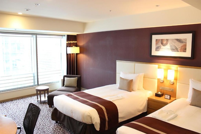 Twin beds and comfortable lounge chair in a guest room in Tokyo’s Ryumeikan Hotel