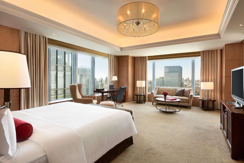 Large suite-style corner room in the Shangri La Tokyo hotel with skyscraper views outside